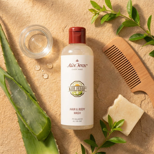 Aloe Ferox hair and body wash bottle with aloe vera leaves, soap, and comb on a beige background