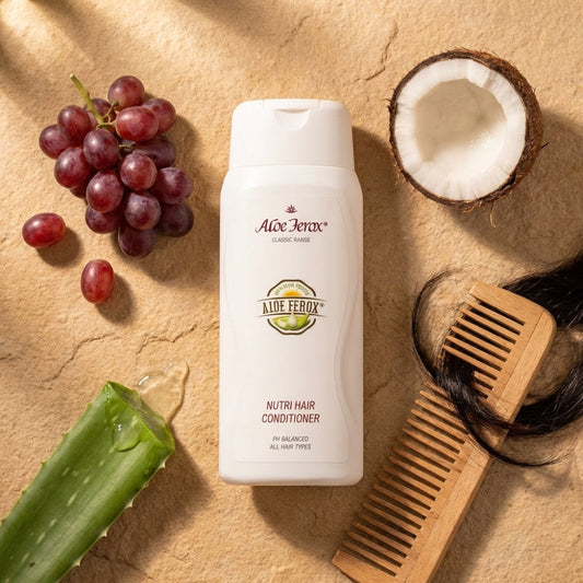 Aloe Ferox hair care product with grapes, a coconut, and a wooden comb on a textured surface
