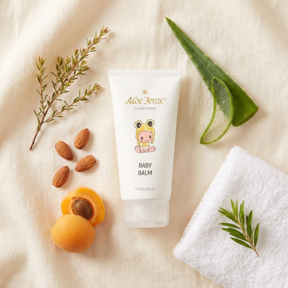 Baby balm with a cartoon character on a beige surface with natural elements like aloe ferox leaf, almonds, and apricots.
