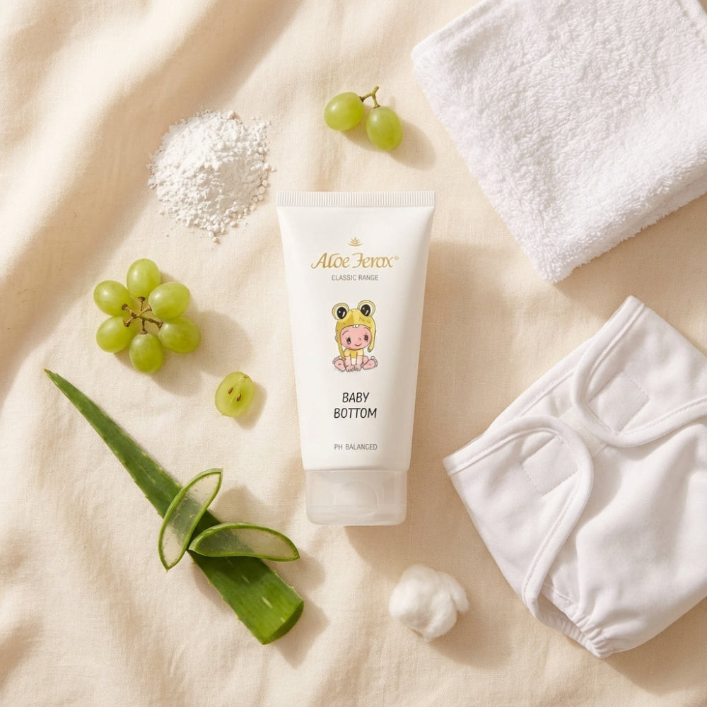 Aloe ferox-based baby product with grapes, aloe leaves, and white diaper on a beige fabric background