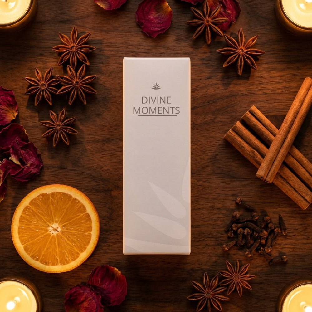 Product packaging labeled 'Divine Moments' surrounded by cinnamon sticks, orange slices, and candles on a wooden surface.