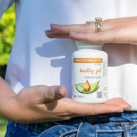 Woman holding a supplement labelled Healthy Gut Awareness Aloe Ferox