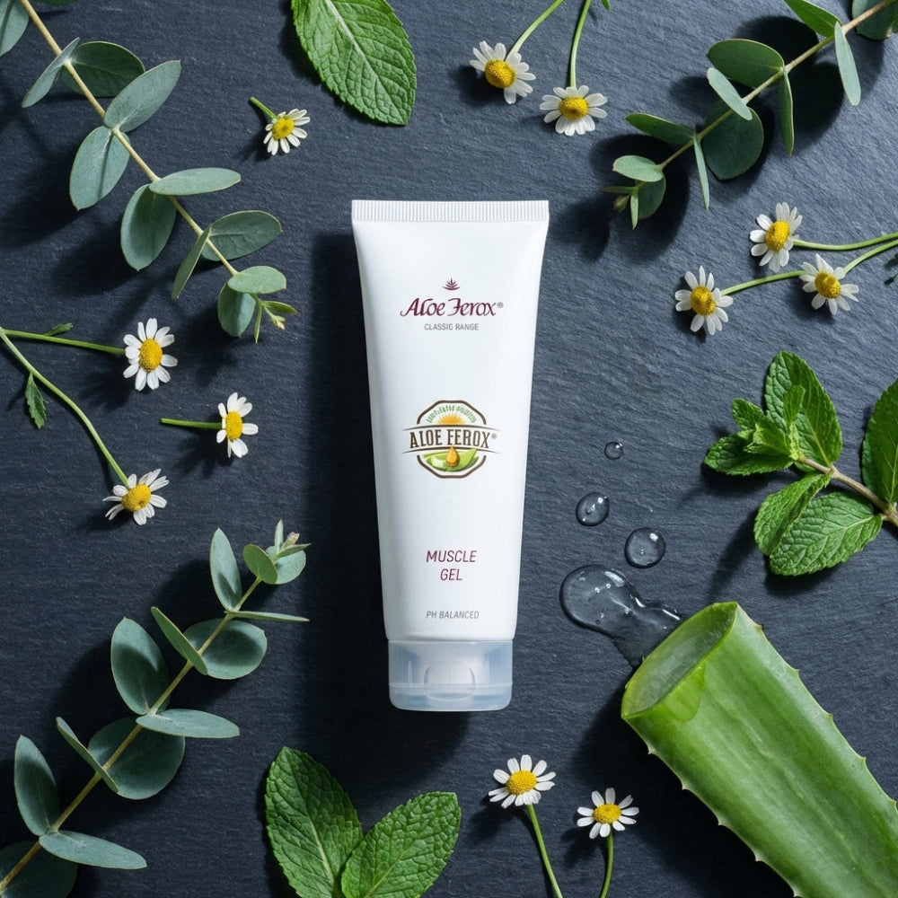 Aloe Vera gel tube surrounded by green leaves and flowers on a dark surface