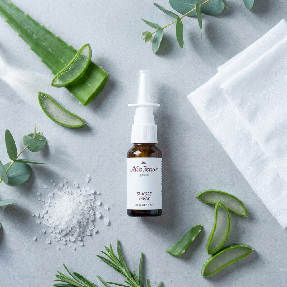 Aloe ferox nose spray bottle on a gray surface with aloe ferox leaves and eucalyptus leaves.