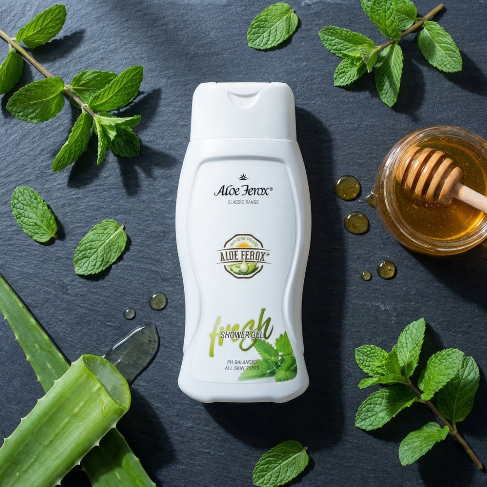 Aloe Ferox shower gel bottle with aloe ferox leaves, honey, and a honey dipper on a dark background