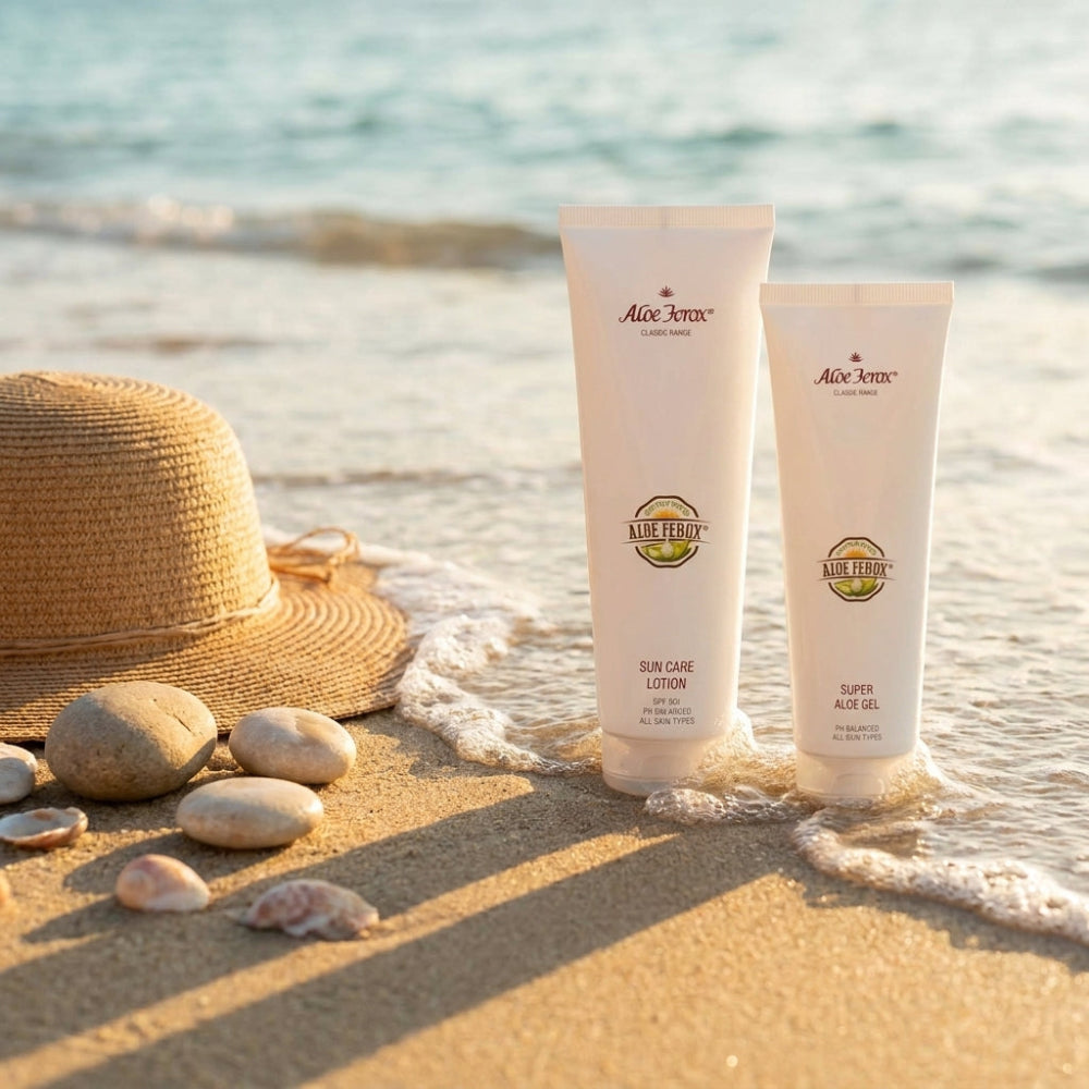 Two Aloe Ferox products on a sandy beach with a hat and shells.