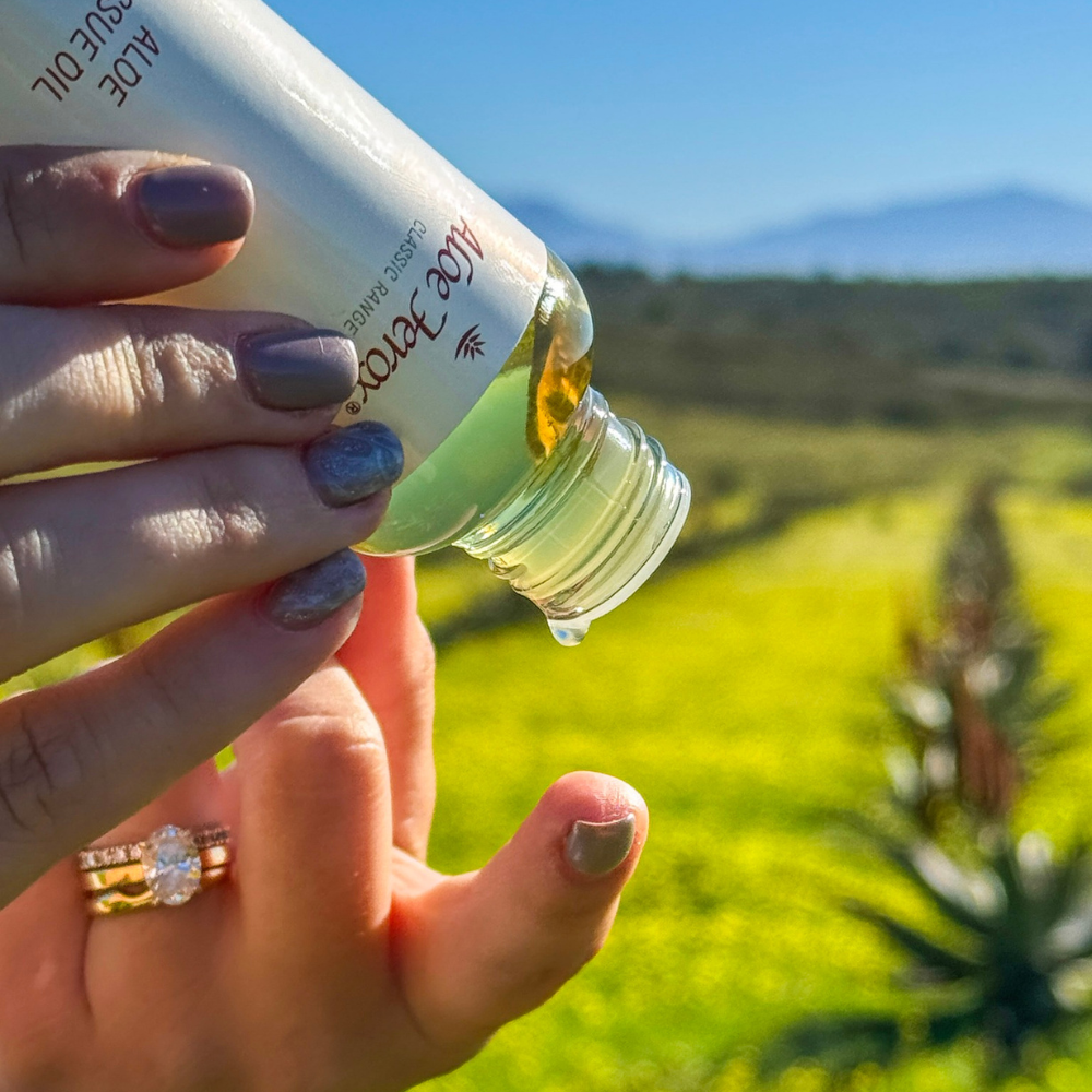Hand holding a bottle of Aloe Ferox tissue oil